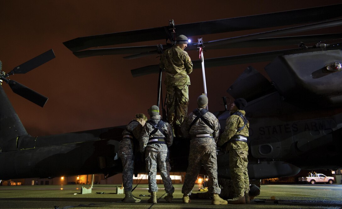 Soldiers work on the main rotor blades of an AH-64 Apache helicopter before being loaded up inside a C-17 Globemaster III in support of large package week operations on Pope Army Airfield, N.C., Feb. 4, 2016. Air Force photo by Staff Sgt. Paul Labbe