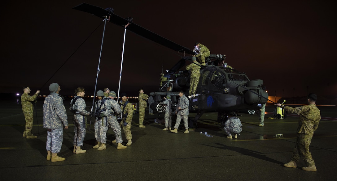 Soldiers and airmen work together to remove the main rotor blades from an AH-64 Apache helicopter before uploading it onboard a C-17 Globemaster III in support of large package week operations on Pope Army Airfield, N.C., Feb. 4, 2016. Air Force photo by Staff Sgt. Paul Labbe