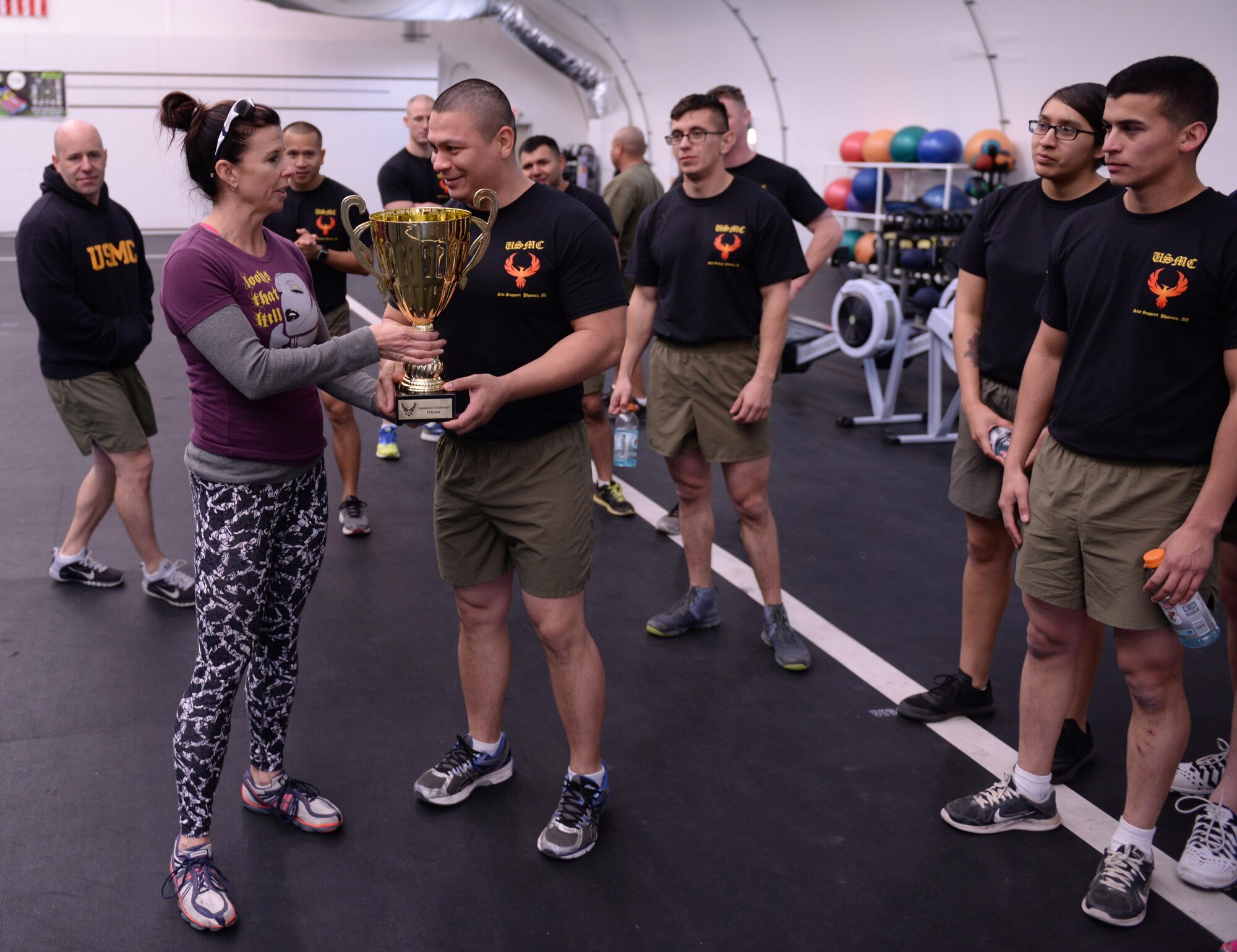 Sherri Biringer, fitness center fitness specialist supervisor, presents the squadron PT challenge trophy to Marine Sgt. Jorge Castellares, 6th Engineer Support Battalion, Feb. 5, 2016, at the Luke Bryant Fitness Center. The trophy enables the Marine detachment to call out or accept any challenge from any Air Force squadron to a squadron PT challenge.