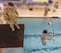 U.S. Army Master Sgt. Joe Medrano, a senior military instructor for Clemson University’s Reserve Officers' Training Corps program from Presidio, Texas, watches as a cadet drops - blindfolded and carrying an M16 - from a 5-meter diving board into a pool during the Combat Water Survival Test, Jan. 28, 2016. (U.S. Army photo by Staff Sgt. Ken Scar)