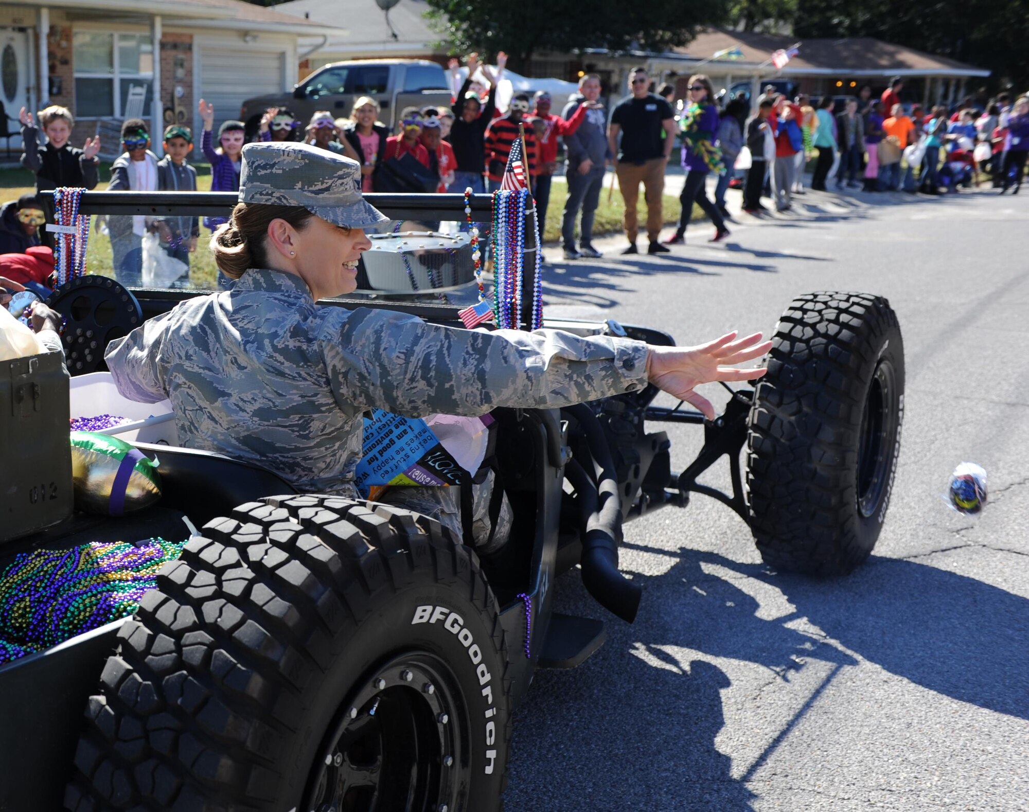 Col. Michele Edmondson, 81st Training Wing commander, throws snack cakes to the crowd during the Jeff Davis Elementary School Mardi Gras Parade, Feb. 5, 2016, Biloxi, Miss. Edmondson and Chief Master Sgt. Harry Hutchinson, 81st TRW command chief, served as Grand Marshalls for the event. (U.S. Air Force photo by Kemberly Groue)