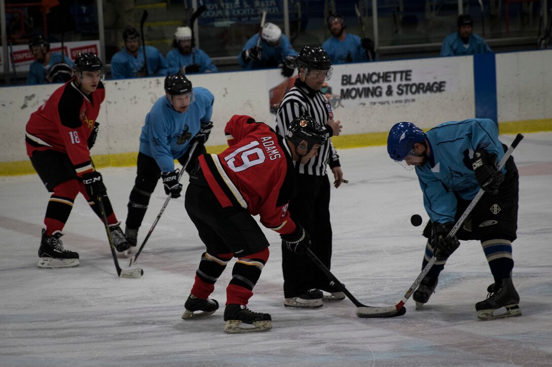 Sergeant Thomas Adams starts a face-off with a member of the Sanford, Maine, police department hockey team during The Maine Event, Battle on Ice hockey tournament, Jan. 15. Adams is one of 15 Marines who came together from across the country to play in the tournament. This is the first time the team has played together and is aiming to create a Marine Corps-recognized All-Marine Ice Hockey Team. Adams is a satellite communications operator with the 3rd Marine Regiment.