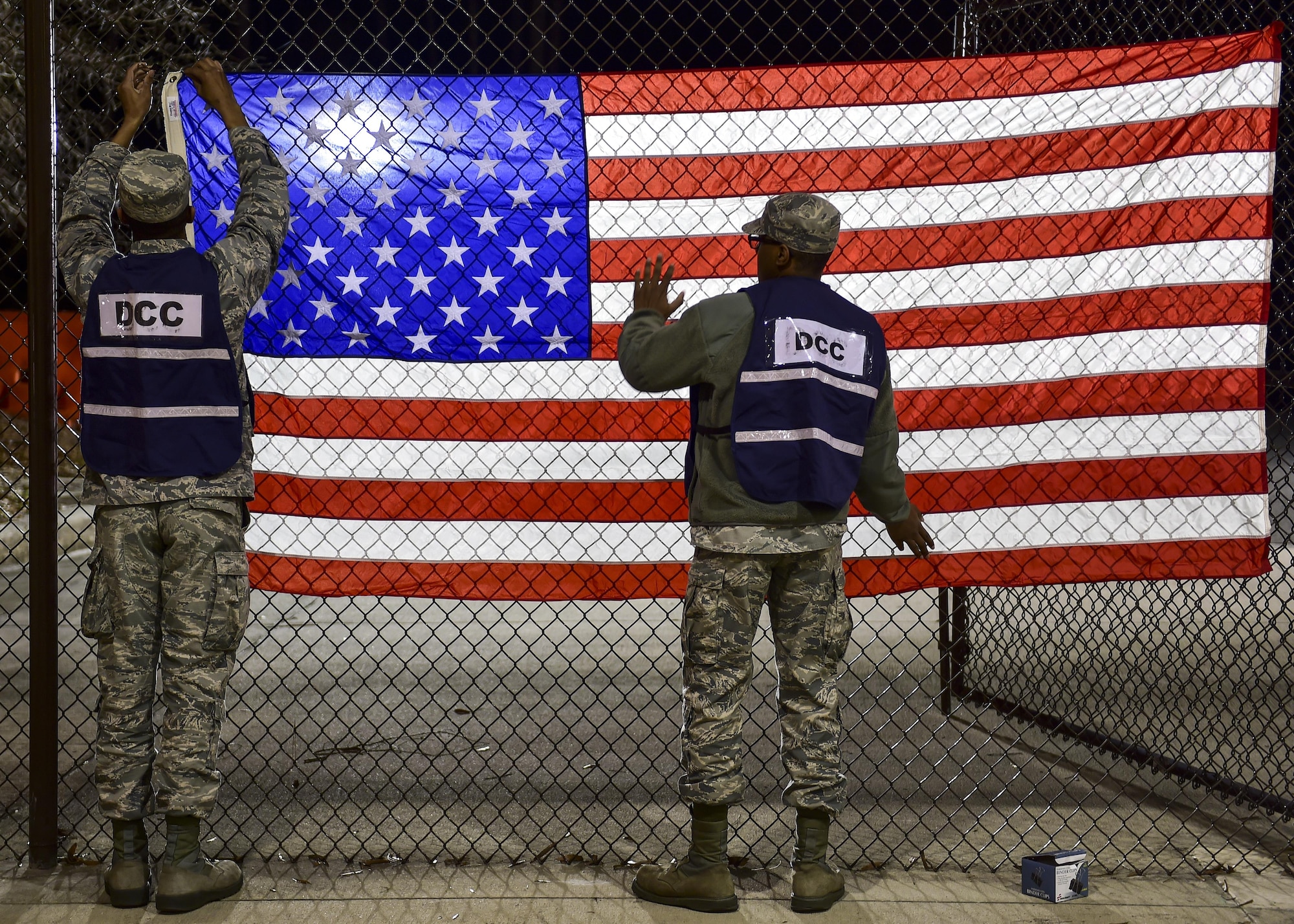Airmen Joshua White and Malik Jenkins, logistics planners with the 1st Special Operations Logistics Readiness Squadron, hang an American flag at the Deployment Control Center on Hurlburt Field, Fla., Feb. 7, 2016. This set the scene for the return of 106 Air Commandos from their deployment overseas. (U.S. Air Force photo by Senior Airman Jeff Parkinson)