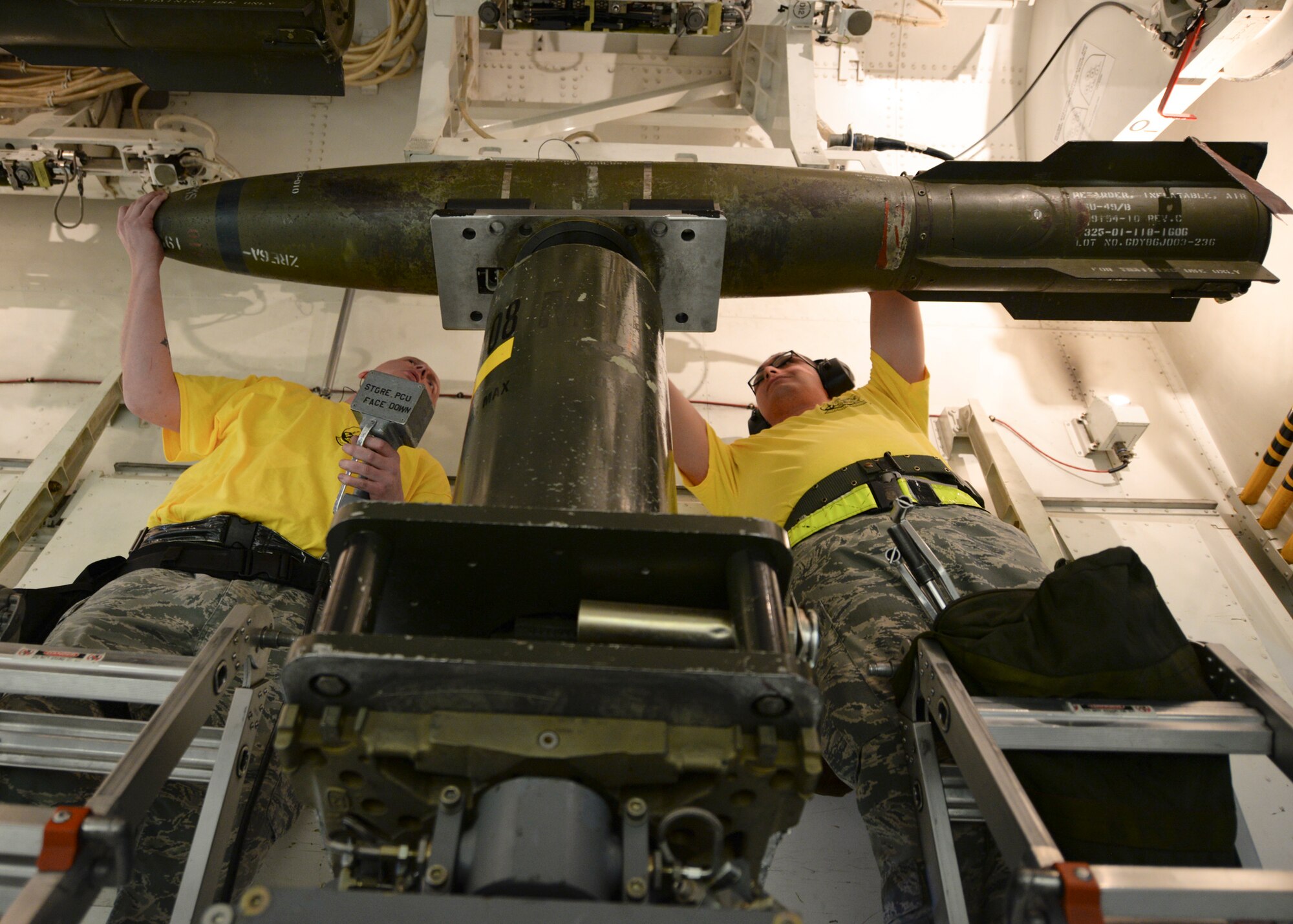 Tech. Sgt. Derek Abbott, 28th Aircraft Maintenance Squadron weapons load crewmember, left, assists Airman 1st Class Ignacio Luna Jr., 28th AMXS weapons load crewmember, with positioning an inert bomb into a training B-1 bomber bomb bay during a load crew of the quarter competition at Ellsworth Air Force Base, S.D., Jan. 29, 2016. Airmen were evaluated on how quickly they loaded munitions according to established procedures and standards – under normal conditions, load times are approximately 40 minutes; however, during the competition, Airmen were challenged to complete the process within 25 minutes. (U.S. Air Force photo by Airman Sadie Colbert/Released)