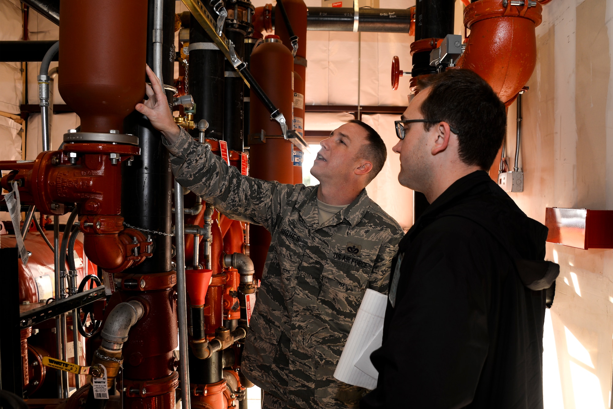 U.S. Air Force Tech. Sgt. Ryan Hughes, 355th Civil Engineer Squadron water fuels system maintenance craftsman, and Andrew Carmean, Air Force Civil Engineer Center Asset Visibility Team civil engineer, inspect a water surge tank inside of a fire protection room during a facility assessment at Davis-Monthan Air Force Base, Ariz., Jan. 28, 2016. D-M AFB is the third base that the AFCEC, Asset Visibilty Team visited during the current fiscal year. (U.S. Air Force photo by Airman 1st Class Mya M. Crosby/Released)