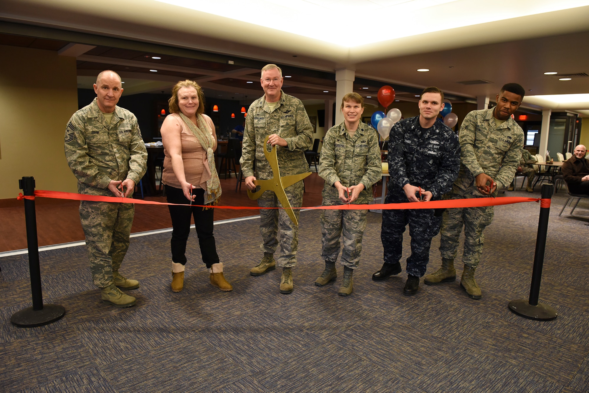 Members of the 911th Airlift Wing and the Navy Operational Support Center Pittsburgh cut the ceremonial ribbon at the grand opening of the new Cargo Bay Community Center, Pittsburgh International Airport Air Reserve Station, Feb. 6, 2016. The new community center houses increased seating with an open concept floor plan, a separate “demilitarized” gaming zone and a new bar. (U.S. Air Force photo by Staff Sgt. Justyne Obeldobel)