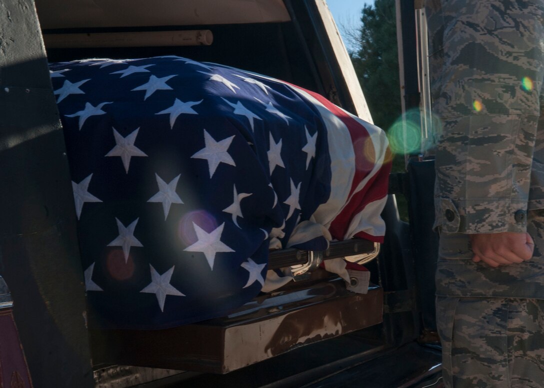 Senior Airman Bradley Glassner, Dyess honor guardsman, stands at attention at the back of a hearse during a practice retiree sequence Feb. 2, 2016, at Dyess Air Force Base, Texas. This routine includes a pall-bearing sequence consisting of six Airmen, followed by a flag folding, firing party, the playing of Taps and a flag presentation during a retiree’s funeral. (U.S. Air Force photo by Airman First Class Katherine Miller/Released)
