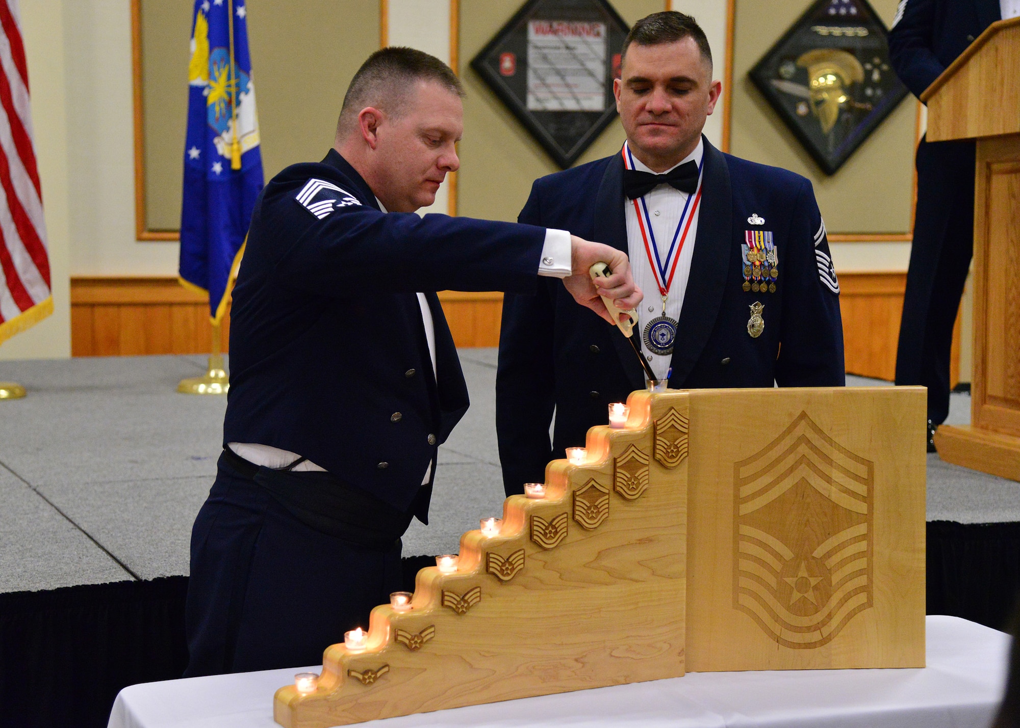 Chief Master Sgt. William Kudrna, 341st Comptroller Squadron superintendent, and Senior Master Sgt. Paul Stansbury, 341st Missile Security Forces Squadron operations superintendent and a chief master sergeant select, light the top candle at the Chief Recognition Banquet held at Malmstrom Air Force Base, Mont., Feb. 5, 2016. The ceremony at the Grizzly Bend recognized their accomplishment of achieving chief master sergeant this year, a rank only one percent of the enlisted force obtains. (U.S. Air Force photo/Airman Daniel Brosam)
