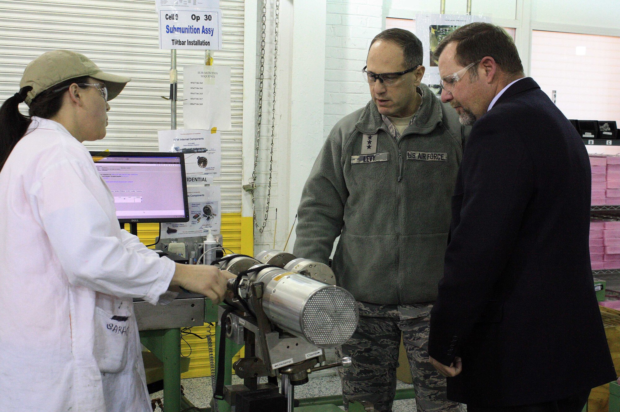 Lauren Miller (left), an explosives production operator, talks to Lt. Gen. Lee K. Levy II, commander, Air Force Sustainment Center at Tinker Air Force Base, Okla., and Chris Scott, McAlester Army Ammunition Plant site leader for Textron Defense Systems, about the CBU-105 Sensor Fuzed Weapon during a visit to the facility in Oklahoma, Jan. 11. (U.S. Army photo by Kevin Jackson)
