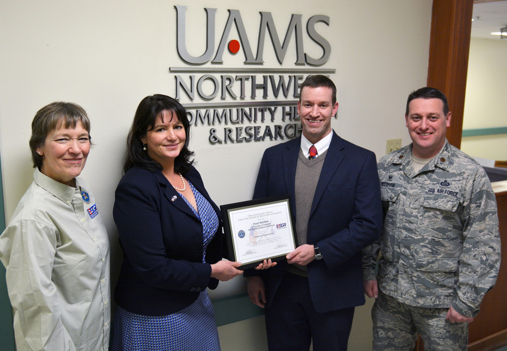 Dr. Pearl McElfish, University of Arkansas for Medical Sciences-Northwest director of the office of community health and research, receives the Employer Support of the Guard and Reserve Patriot Award Jan. 1, 2016, from Lt. Col. Judith Mathewson, left, Master Sgt. Michael Stephens, centers for disease control and prevention program director at UAMS-Northwest, and Maj. Paul Needham, commander of the 288th Operations Support Squadron, at UAMS-Northwest in Fayetteville, Ark. McElfish is receiving the award for contributing to national security and protecting liberty and freedom by supporting employee participation in America’s National Guard and Reserve force. Stephens is a first sergeant in the 288th OSS as a drill-status guardsman. (Courtesy photo)
