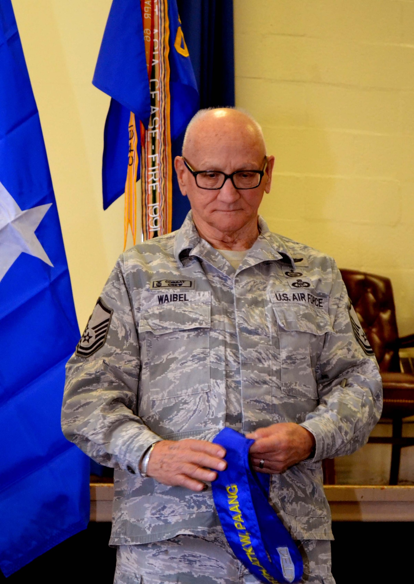 Retired Master Sgt. Jim Waibel, the 111th Attack Wing historian, clutches the 111th Air Operations Group streamer after it had been removed during a deactivation ceremony held Feb. 6, 2016 at Horsham Air Guard Station, Pennsylvania. The 111th AOG was a high-tempo operations group on base for five years. (U.S. Air National Guard photo by Tech. Sgt. Andria Allmond)