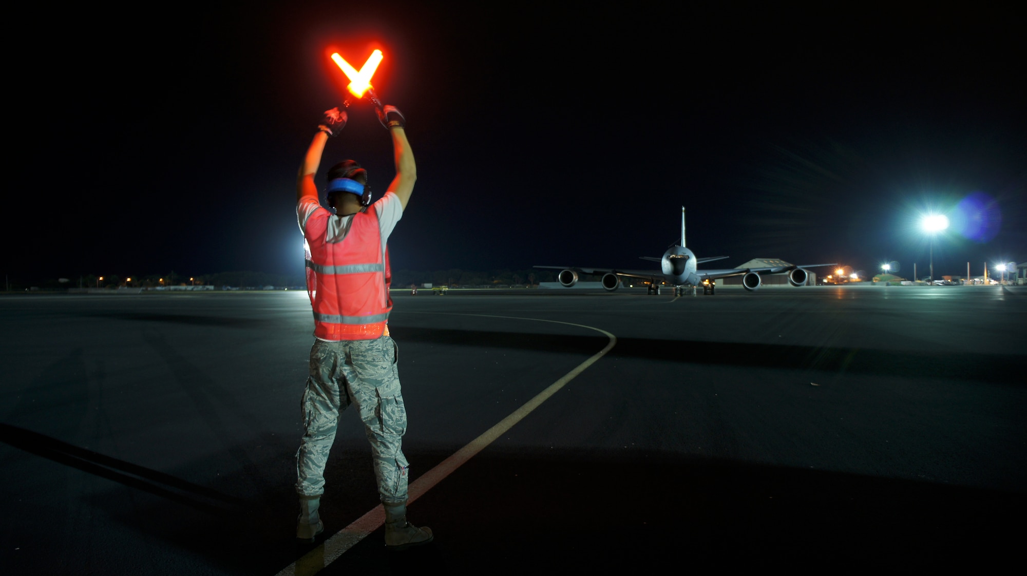 A Hawaii Air National Guard ground crew member prepares to marshal out a KC-135 Stratotanker for departure to its deployment to Southwest Asia to join the 18-nation air coalition in the fight against Daesh, Feb 05, 2016 Joint Base Pearl Harbor-Hickam (U.S. Air National Guard photo by Tech. Sgt Andrew Jackson/released).