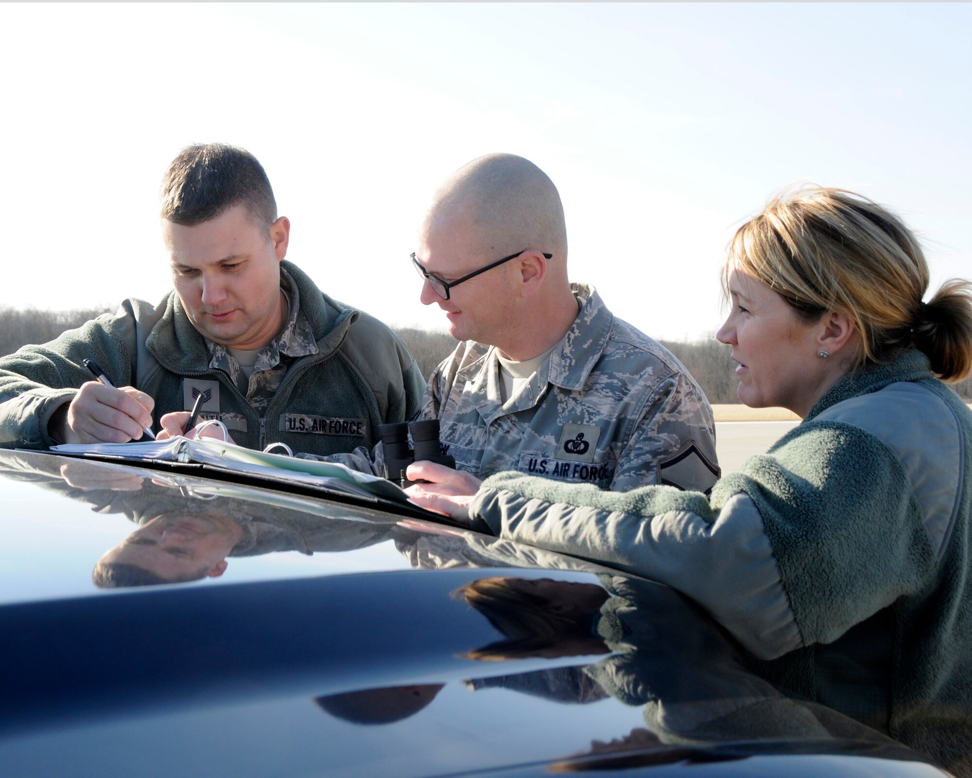 (Left to right) Tech. Sgt. Jared Smith, Master Sgt. Brent Bixby, and Master Sgt. Christina Ericson from the 182nd Airlift Wing's Airfield Management office document the calculations needed to determine the maximum allowable height of a communications antenna placed on the airfield at the General Wayne A. Downing Peoria International Airport in Peoria, Ill. Feb. 7, 2016. (U.S. Air National Guard photo  by Tech. Sgt. Todd Pendleton) 