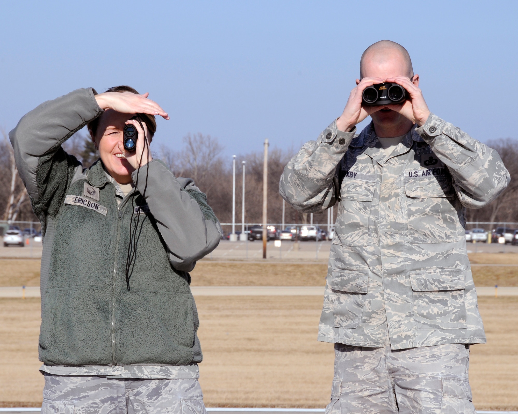 Master Sgt. Christina Ericson and Master Sgt. Brent Bixby from the 182nd Airlift Wing's Airfield Management office use a laser range finder and binoculars from the runway centerline to take the measurement of a communications antenna placed on the airfield of the General Wayne A. Downing International Airport in Peoria, Ill. Feb. 7, 2016. (U.S. Air National Guard photo  by Tech. Sgt. Todd Pendleton)