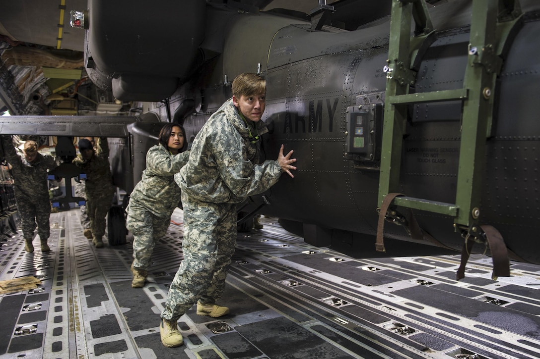 Soldiers and airmen work together to upload an AH-64 Apache helicopter onboard a C-17 Globemaster III in support of large package week operations on Pope Army Airfield, N.C., Feb. 4, 2016. Air Force photo by Staff Sgt. Paul Labbe