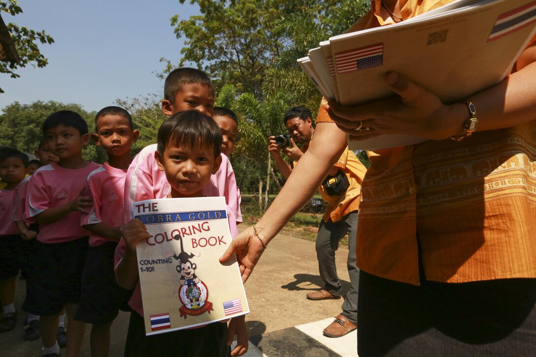 Chomanee Chomnamul, an elementary school teacher at Ban Sa Yai School in Trat, Thailand, passes out coloring books during exercise Cobra Gold, Feb. 3, 2016. Cobra Gold 2016, in its 35th iteration, includes a specific focus on humanitarian civic action, community engagement and medical activities conducted during the exercise to support the needs and humanitarian interests of civilian populations around the region.