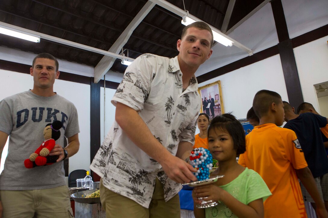 Cpl. Christopher Medieros accepts a gift of appreciation from a local Thai child at the Children Development and Protection Center in Thailand Feb. 6, 2016. Marines of the 31st Marine Expeditionary Unit are in Thailand for Cobra Gold 16, an exercise designed to increase cooperation, interoperability and collaboration among partner nations in order to achieve effective solutions to common challenges. Medieros, a native of Boston, Massachusetts, is an infantry squad leader with 1st Battalion 5th Marines, 31st Marine Expeditionary Unit. 