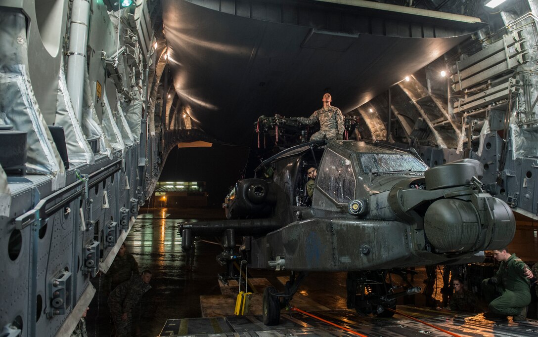 Soldiers and airmen load an Army AH-64 Apache helicopter onto an Air Force C-17 Globemaster III in support of "large package week" operations at Pope Army Airfield, N.C., Feb. 4, 2016. Air Force photo by Staff Sgt. Gregory Brook