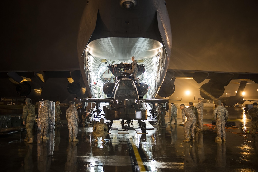 Soldiers and airmen load an Army AH-64 Apache helicopter onto an Air Force C-17 Globemaster III in support of "large package week" operations at Pope Army Airfield, N.C., Feb. 4, 2016. Air Force photo by Staff Sgt. Gregory Brook