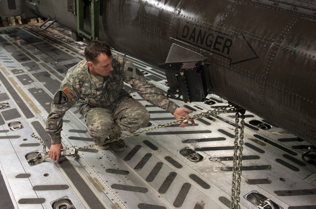 A soldier tightens chains securing an Army AH-64 Apache helicopter to the floor of an Air Force C-17 Globemaster III in support of "large package week" operations at Pope Army Airfield, N.C., Feb. 4, 2015. The soldier is assigned to the 82nd Airborne Division’s 82nd Combat Aviation Brigade. Air Force photo by Staff Sgt. Gregory Brook