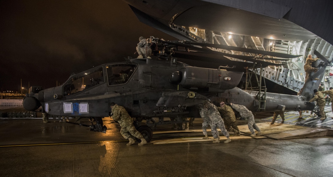 Soldiers and airmen transport an Army AH-64 Apache helicopter after unloading it from an Air Force C-17 Globemaster III during "large package week" operations at Pope Army Airfield, N.C., Feb. 4, 2015. Air Force photo by Staff Sgt. Gregory Brook