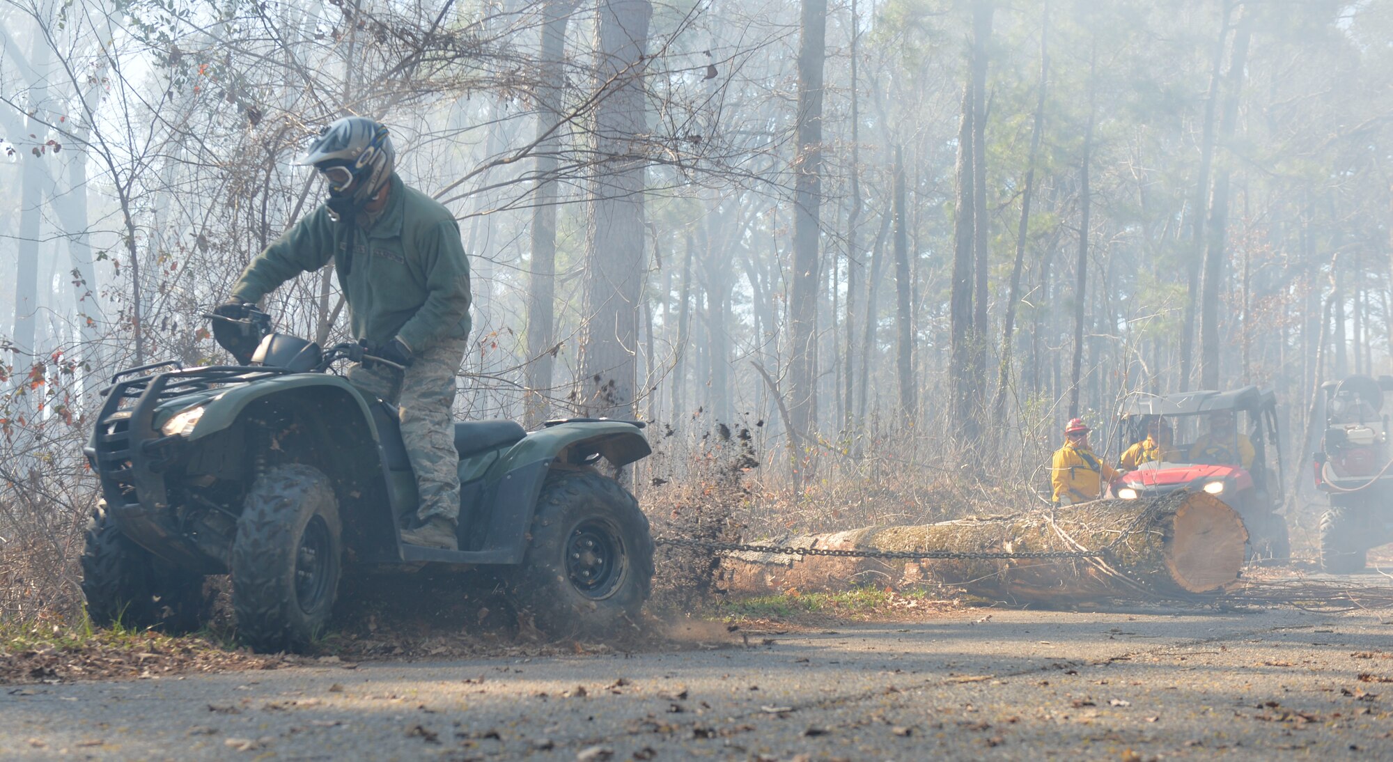 Staff Sgt. Mike Meserole, 2nd Security Forces Squadron game warden, assists natural resources technicians in moving a downed tree at Barksdale Air Force Base, La., Feb. 4, 2016. Meserole provided help monitoring fire lines, clearing pathways and directing traffic during a controlled burn event. (U.S. Air Force photo/Airman 1st Class Mozer O. Da Cunha)