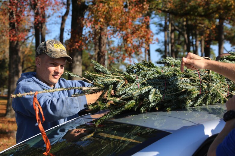 Lance Cpl. Blake Greil ties a tree to a vehicle during the 10th annual trees for troops event at Marine Corps Air Station Cherry Point, N.C., Dec. 8, 2015. More than 400 free trees were distributed to service members and their families as a symbol of brotherhood and appreciation from the community during the holiday season. Greil is a bulk fuel specialist with Marine Wing Support Squadron 274. (U.S. Marine Corps photo by Cpl. N.W. Huertas/Released)