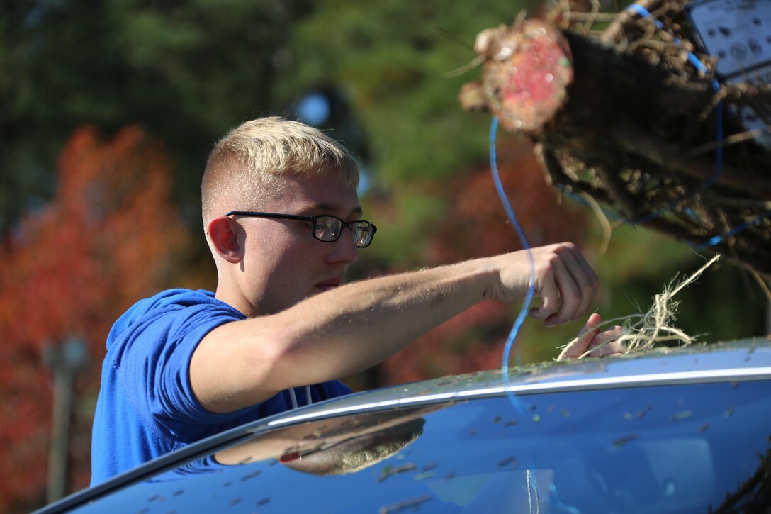Private first class Sidney Livingston ties a tree to a vehicle during the 10th annual trees for troops event at Marine Corps Air Station Cherry Point, N.C., Dec. 8, 2015. More than 400 free trees were distributed to service members and their families as a symbol of brotherhood and appreciation from the community during the holiday season. Livingston is a bulk fuel specialist with Marine Wing Support Squadron 274. (U.S. Marine Corps photo by Cpl. N.W. Huertas/Released)