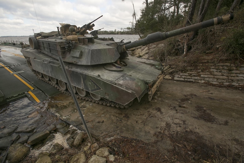 Marines with Bridge Company, 8th Engineer Support Battalion, roll an M1A1 Abrams tank off of a seven-bay raft system after being transported across New River during a water-crossing operation at Camp Lejeune, N.C., Feb. 4, 2016. The unit boasts a wide range of raft systems and bridging that it is able to do to allow tactical vehicles to cross large bodies of water. (U.S. Marine Corps photo by Lance Cpl. Damarko Bones/Released)