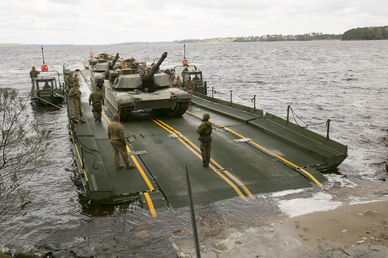 Marines with Bridge Company, 8th Engineer Support Battalion, prepare to unload two M1A1 Abrams tanks following their transport across New River by using a seven-bay raft system during a water-crossing operation at Camp Lejeune, N.C., Feb. 4, 2016. The unit boasts a wide range of raft systems and bridging equipment, which enables tactical vehicles to cross large bodies of water. (U.S. Marine Corps photo by Lance Cpl. Damarko Bones/Released)