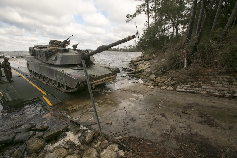 Marines with Bridge Company, 8th Engineer Support Battalion, roll an M1A1 Abrams tank off of a seven-bay raft system after being transported across New River during a water-crossing operation at Camp Lejeune, N.C., Feb. 4, 2016. The company specializes in allowing units to travel over bodies of water, which in turn increases the mobility of the unit being transported. (U.S. Marine Corps photo by Lance Cpl. Damarko Bones/Released)
