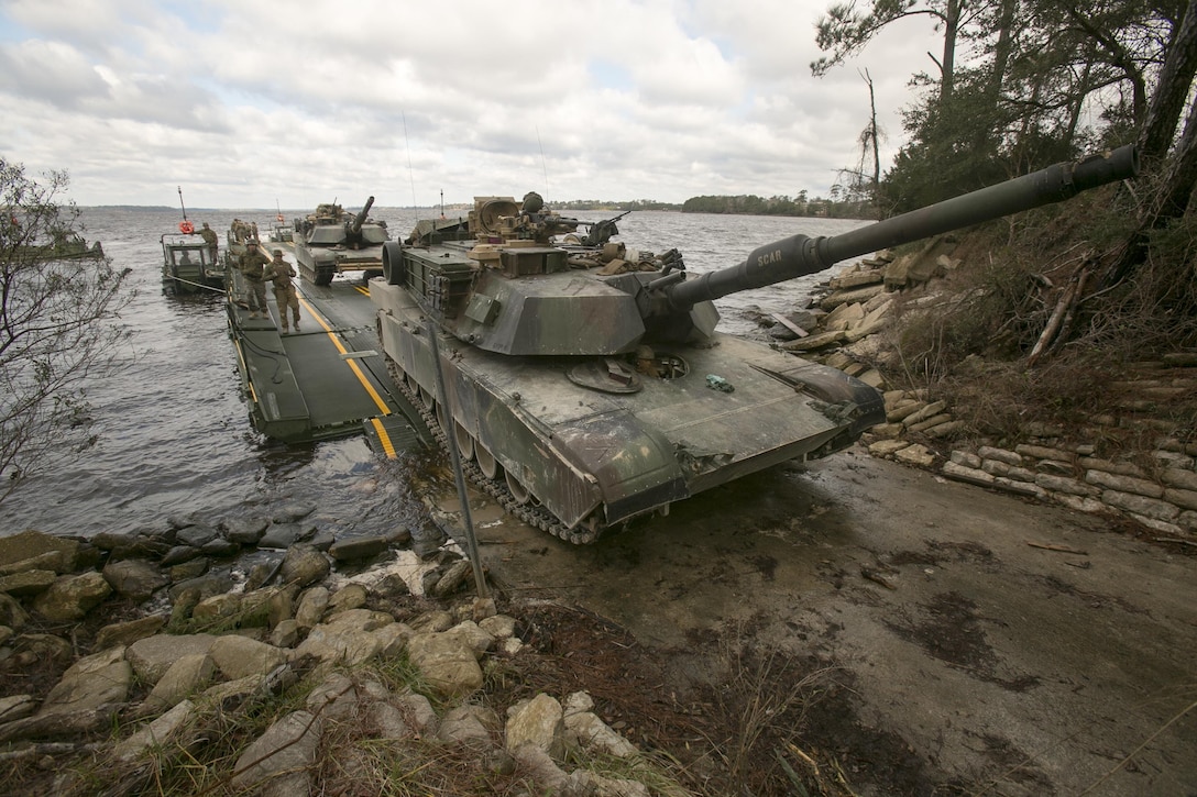 Marines with Bridge Company, 8th Engineer Support Battalion, roll an M1A1 Abrams tank off of a seven-bay raft system after being transported across New River during a water-crossing operation at Camp Lejeune, N.C., Feb. 4, 2016. The company specializes in allowing units to travel over bodies of water, which in turn increases the mobility of the unit being transported. (U.S. Marine Corps photo by Lance Cpl. Damarko Bones/Released)