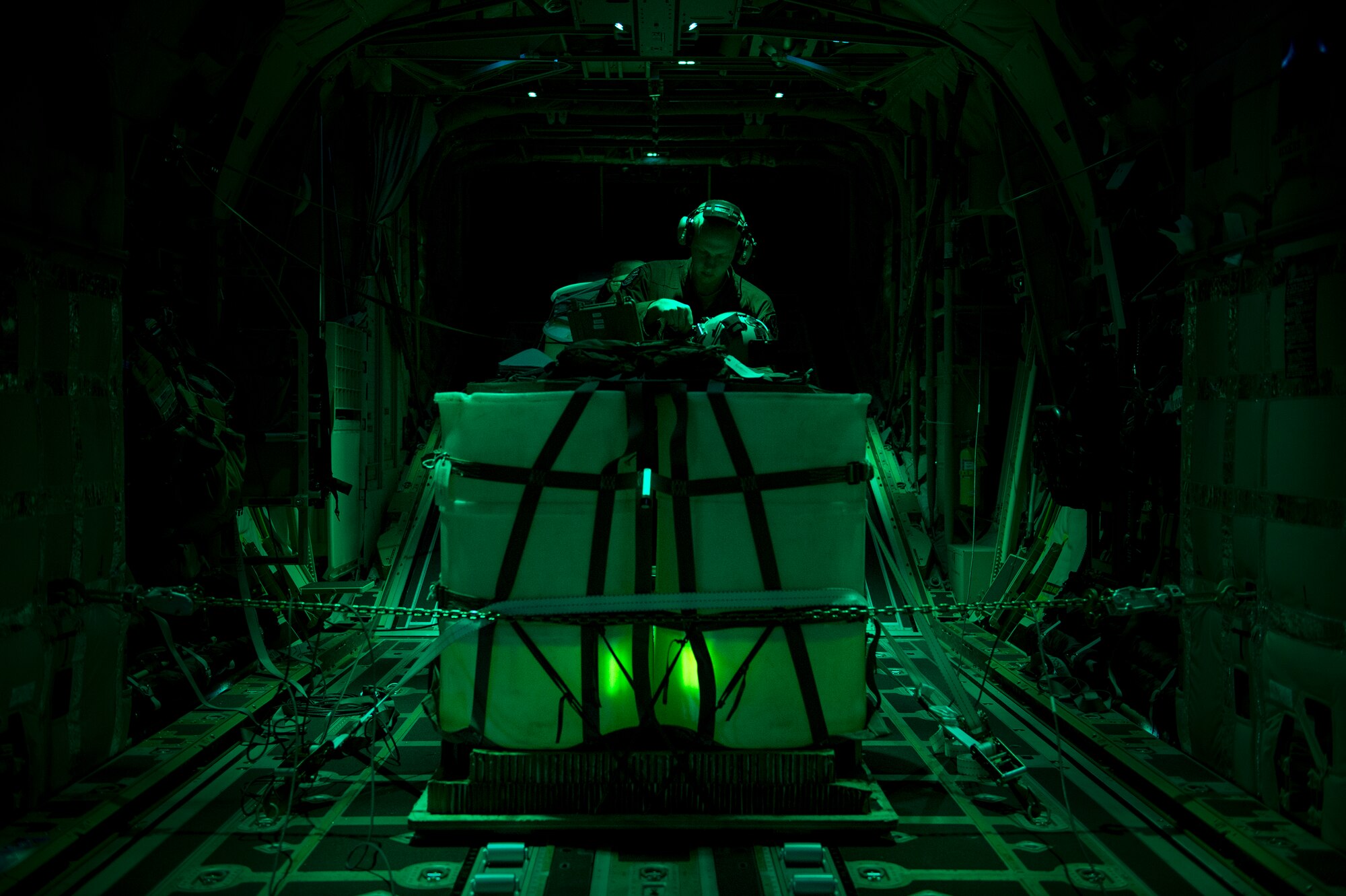 U.S. Air Force Senior Airman Timothy Foote, 71st Rescue Squadron loadmaster, prepares his helmet and night vision goggles prior to an air drop in an HC-130J Combat King II, Feb. 2, 2016 in the skies over Moody Air Force Base, Ga. Crews use NVGs for tactical flight profiles to avoid detection to accomplish covert infiltration, exfiltration and transload operations. (U.S. Air Force photo by Senior Airman Ryan Callaghan/Released)



