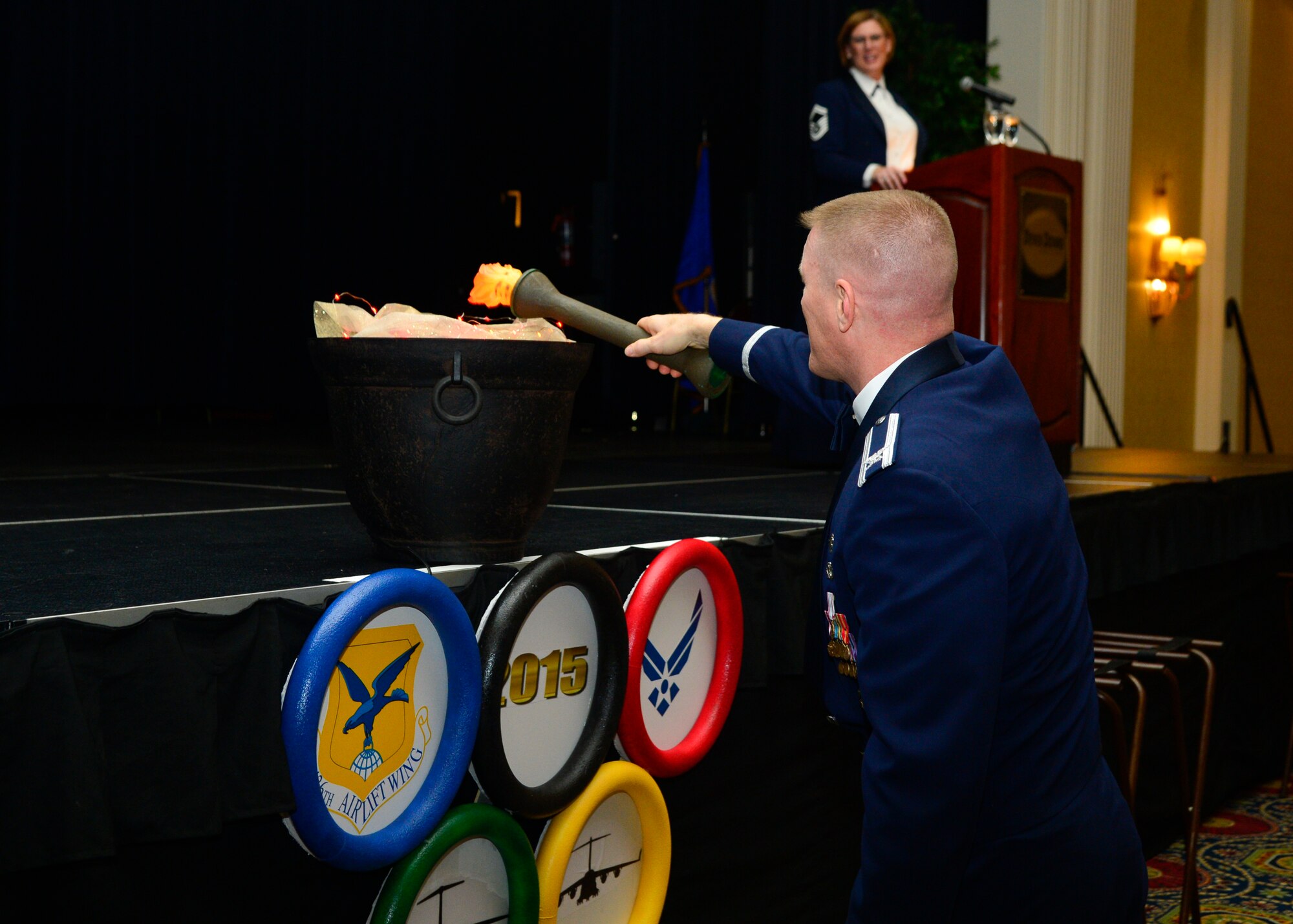Col. Michael Grismer, 436th Airlift Wing commander, lights the ceremonial fire at the start of the 2015 436th Airlift Wing Annual Awards Ceremony Jan. 5, 2016, at the Rollins Center in Dover, Del. This year’s theme was “Going for the Gold.” (U.S. Air Force photo/Senior Airman William Johnson)