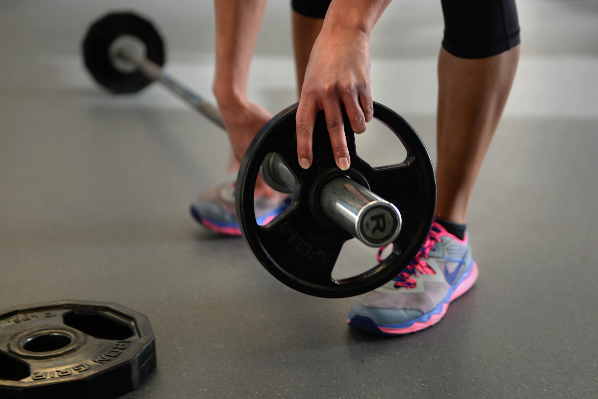 A beginner athlete in the newly offered tactical fitness class, OnRamp, adds a 10-lb weight to a barbell at the McAdoo Fitness Center Feb. 4, 2016. OnRamp focuses on the form and mechanics of workouts such as bent over rows and dead-lifts. (U.S. Air Force photo/Airman 1st Class Jessica Weissman)