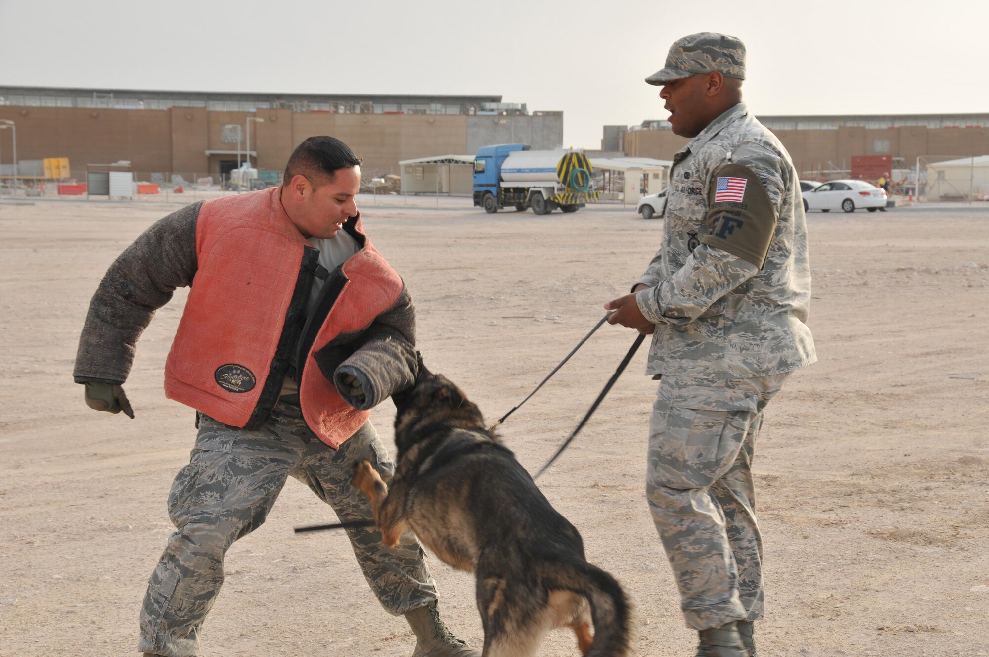 Tech. Sgt. Max Soto (left), 379th Expeditionary Security Forces Squadron military working dog trainer and Staff Sgt. Jahmal Hardy (right), 379 ESFS MWD handler, along with Nero, Hardy’s partner, practice patrol training Jan. 27 at Al Udeid Air Base Qatar. In this training scenario, Soto plays the role of a suspicious suspect attempting to escape and Nero must stop him. (U.S. Air Force photo by Tech. Sgt. Terrica Y. Jones/Released)