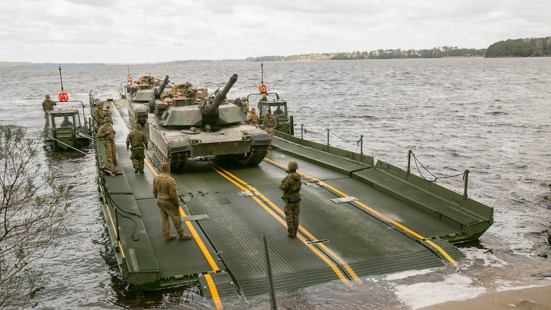Marines with Bridge Company, 8th Engineer Support Battalion, prepare to unload two M1A1 Abrams tanks following their transport across New River by using a seven-bay raft system during a water-crossing operation at Marine Corps Base Camp Lejeune, N.C., Feb. 4, 2016. The unit boasts a wide range of raft systems and bridging equipment, which enables tactical vehicles to cross large bodies of water. 
