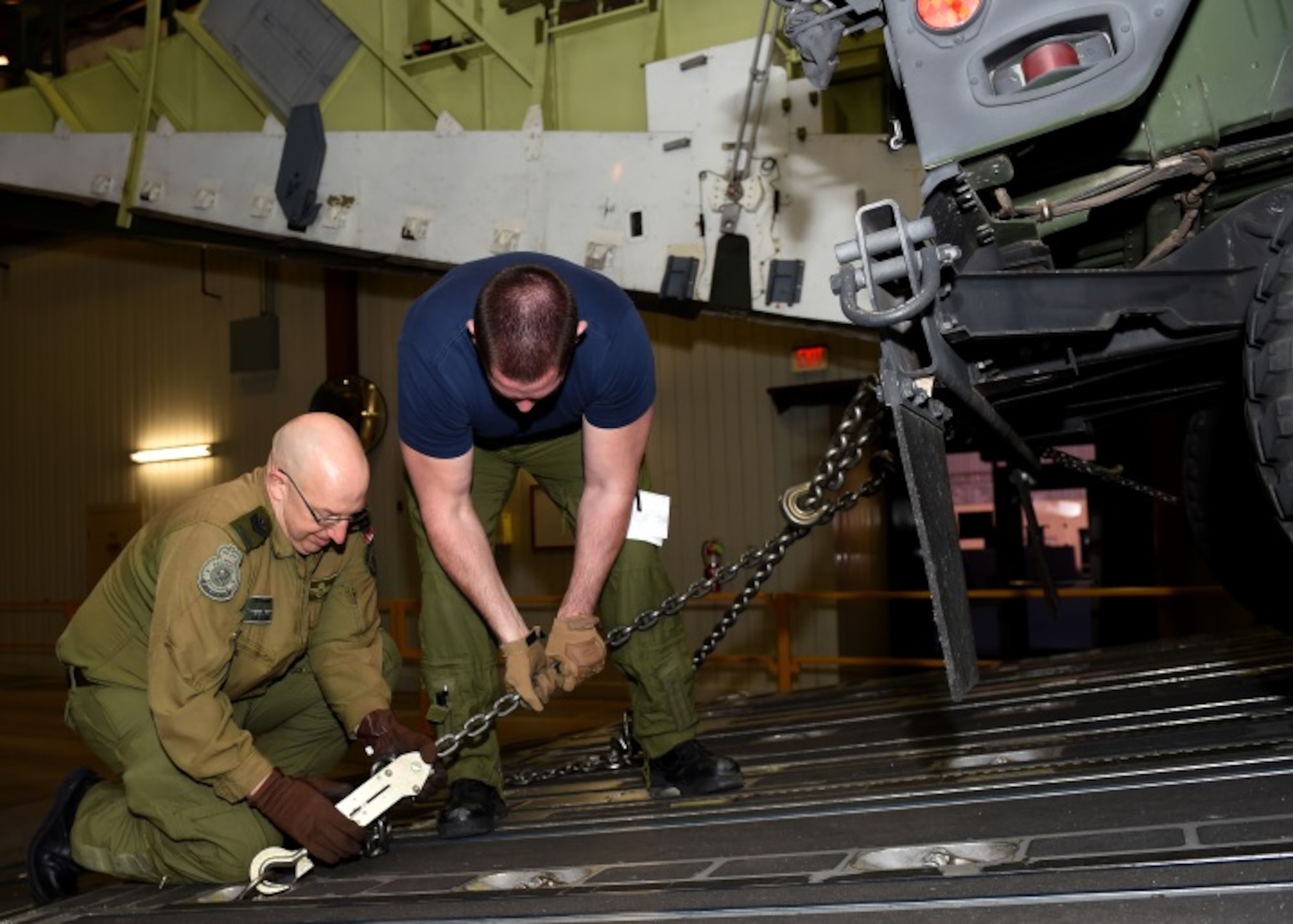 Royal Canadian air force Sgt. David Burrill and Royal Canadian air force Master Corporal Derek Bristol, Globemaster III cargo aircraft loadmaster trainees, secure a vehicle inside a C-17 Globemaster III cargo simulator at Altus Air Force Base, Okla., Dec. 16, 2015. Training international students helps improve joint nation missions with uniformed knowledge and operations. (U.S. Air Force photo by Airman 1st Class Kirby Turbak/Released)