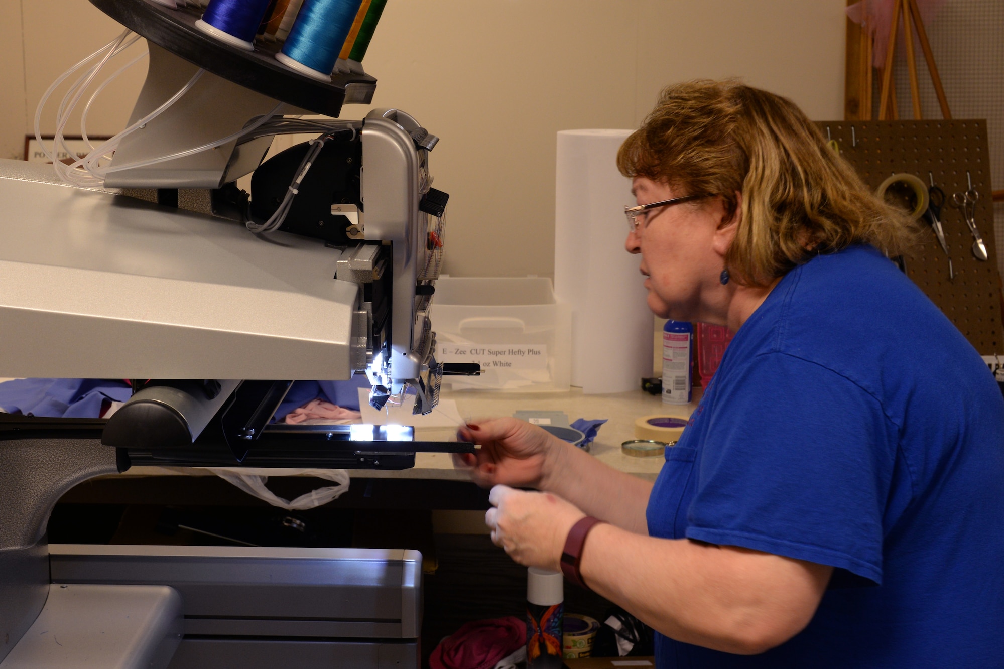 Linda Bowers, Arts and Crafts Center framer & embroiderer, threads a needle through an embroidery machine Feb. 2, 2016, Keesler Air Force Base, Miss. The embroidery shop is a newly opened segment of the Arts and Crafts Center that embroiders everything from baby clothes to name tapes. (U.S. Air Force photo by Airman 1st Class Travis Beihl)