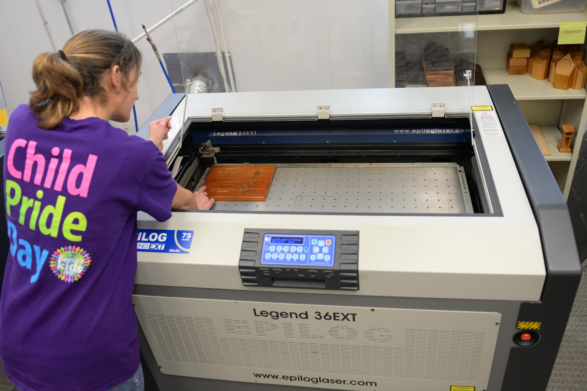 Miguele Couvillion, Arts and Crafts Center engraver, removes a plaque from the L.A.S.E.R. engraver Feb. 2, 2016, Keesler Air Force Base, Miss. The L.A.S.E.R. engraver is able to personalize several items including pieces of wood, drinking glasses and metal thermoses. (U.S. Air Force photo by Airman 1st Class Travis Beihl)