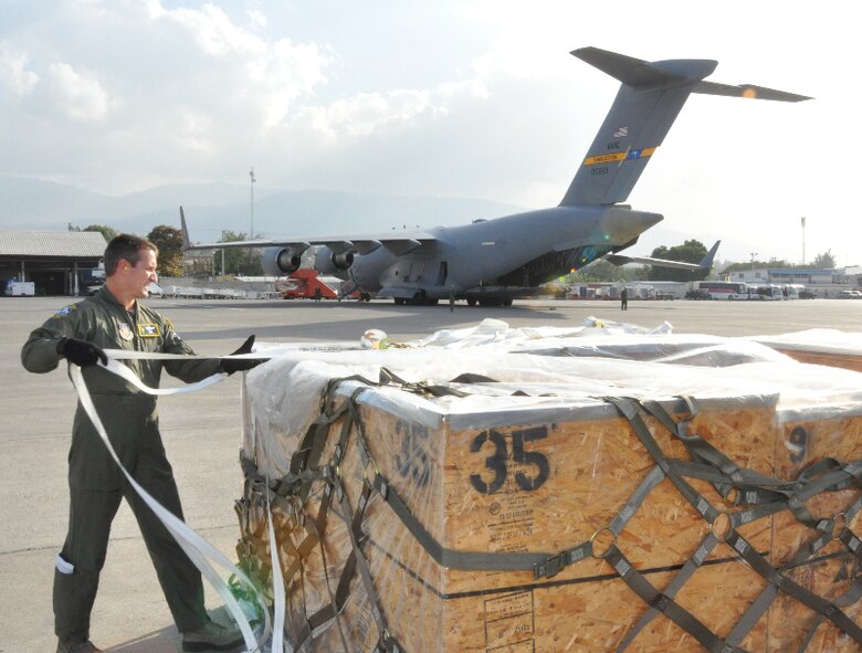 Master Sgt. Ken Hundemer, a 317th Airlift Squadron loadmaster, removes cargo straps from humanitarian aid in Port Au Prince Haiti. (U.S. Air Force photo by Maj. Wayne Capps)