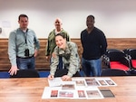 DLA Distribution Europe commander Army Lt. Col. Krista Hoffman signs the last official receipt for the Intermediate Staging Base in Incirlik, Turkey, alongside Matt Merrill, chief of Operations Division, far left, Richard Holland, accountable officer, back center, and Derrick White, chief of Inventory Division, far right.