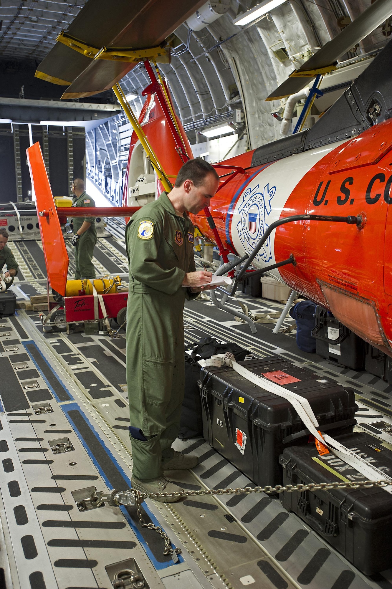 Tech. Sgt. Michael Smith, a loadmasters assigned to the 300th Airlift Squadron, Joint Base Charleston, South Carolina, conducts pre-flight checklists of the cargo, a U.S. Coast Guard MH-65 Dolphin helicopte, prior to departure. Reservists assigned to the 300 AS assisted the U.S. Coast Guard with transporting several MH-65 Dolphin helicopters and various supplies Feb. 5-7, 2016. (U.S. Air Force photo by SSgt. Bobby Pilch)