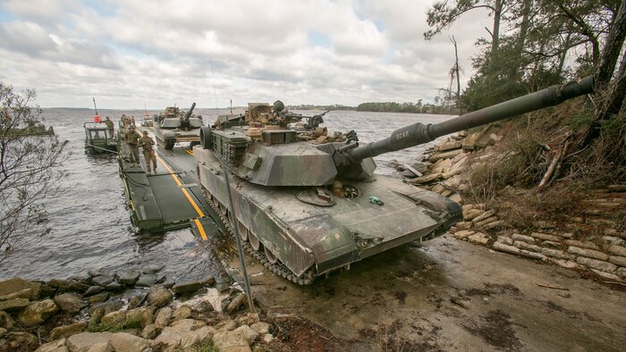 Marines with Bridge Company, 8th Engineer Support Battalion, roll an M1A1 Abrams tank off of a seven-bay raft system after being transported across New River during a water-crossing operation at Marine Corps Base Camp Lejeune, N.C., Feb. 4, 2016. The company specializes in allowing units to travel over bodies of water, which in turn increases the mobility of the unit being transported. 