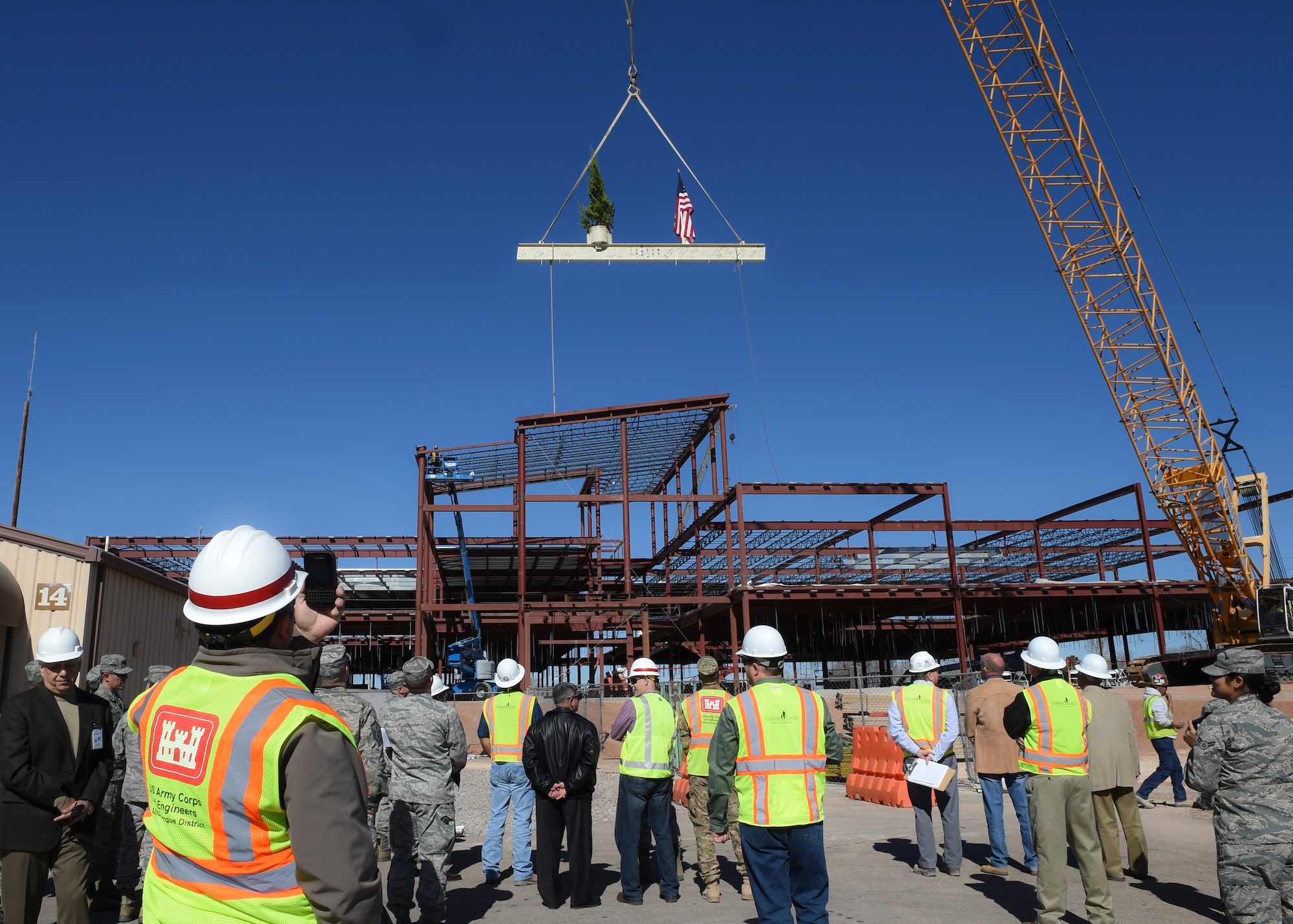 Members of Team Holloman and construction workers gather to witness the “Topping Out” of the last beam being placed on the new medical facility at Holloman Air Force Base, N.M. on Feb. 10. The tradition of “Topping Out” has become a custom of ironworkers, whenever the skeleton of a building is completed. Topping Out is a signal that the uppermost steel member is going into place, and the structure has reached its planned height. As that final beam is hoisted, an evergreen tree, a flag or both are attached to it. (U.S. Air Force photo by Senior Airman Leah Ferrante)