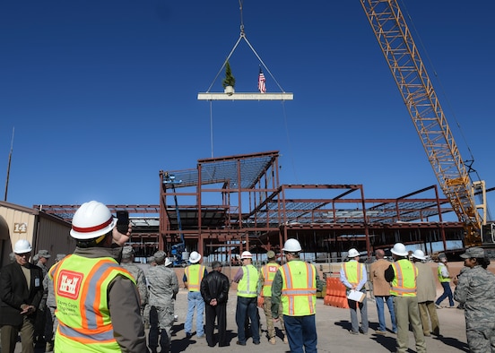Members of Team Holloman and construction workers gather to witness the “Topping Out” of the last beam being placed on the new medical facility at Holloman Air Force Base, N.M. on Feb. 10. The tradition of “Topping Out” has become a custom of ironworkers, whenever the skeleton of a building is completed. Topping Out is a signal that the uppermost steel member is going into place, and the structure has reached its planned height. As that final beam is hoisted, an evergreen tree, a flag or both are attached to it. (U.S. Air Force photo by Senior Airman Leah Ferrante)