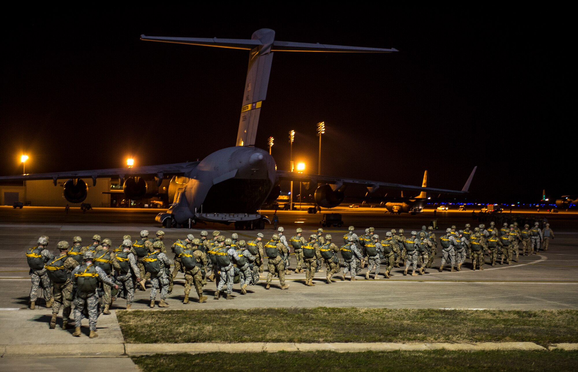 U.S. Army Soldiers with the 1st Battalion, 504th Parachute Infantry Regiment, 1st Brigade Combat Team, 82nd Airborne Division, make their way to their aircraft for a night static-line jump on Sicily Drop Zone during Large Package Week at Pope Army Airfield, N.C., Feb. 7, 2016. Large Package Week leads up to Joint Operational Access Exercise 16-5, where in Army and Air Force units work together to improve interoperability for worldwide crisis, contingency and humanitarian operations. (U.S. Air Force photo by Staff Sgt. Marianique Santos)