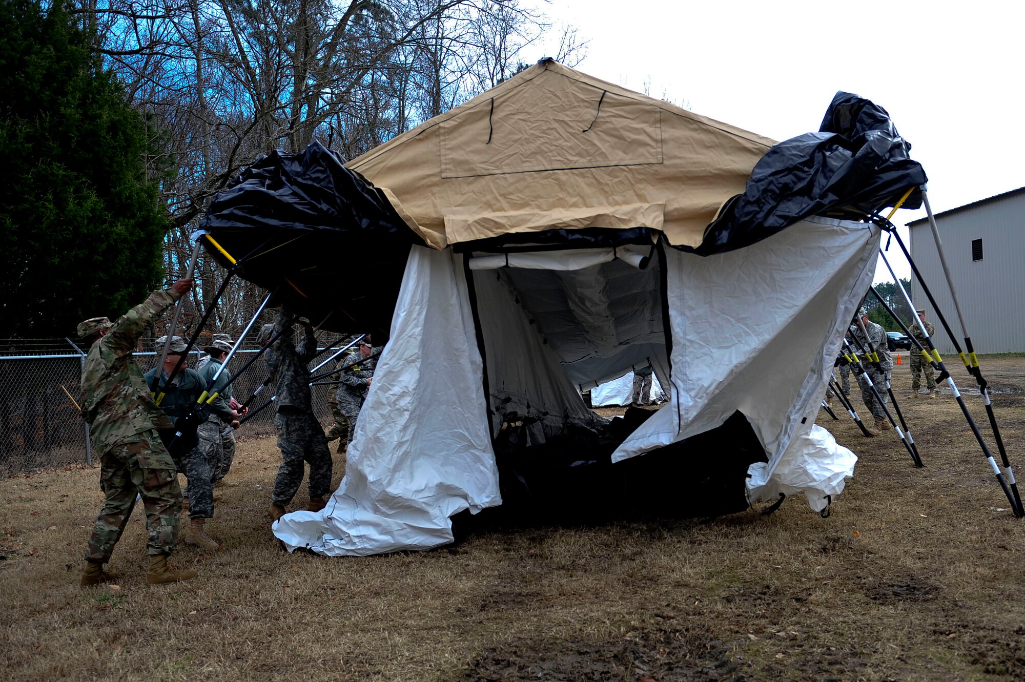 U.S. Army Soldiers from the 833rd Transportation Battalion lift their side of the tent during a command post exercise at Fort Eustis, Va., Feb. 9, 2016. The new tents are designed to cut down building time from four to six hours to approximately30 minutes, ensuring the mission is completed in a timely manner.  (U.S. Air Force photo by Airman 1st Class Breonna Veal)