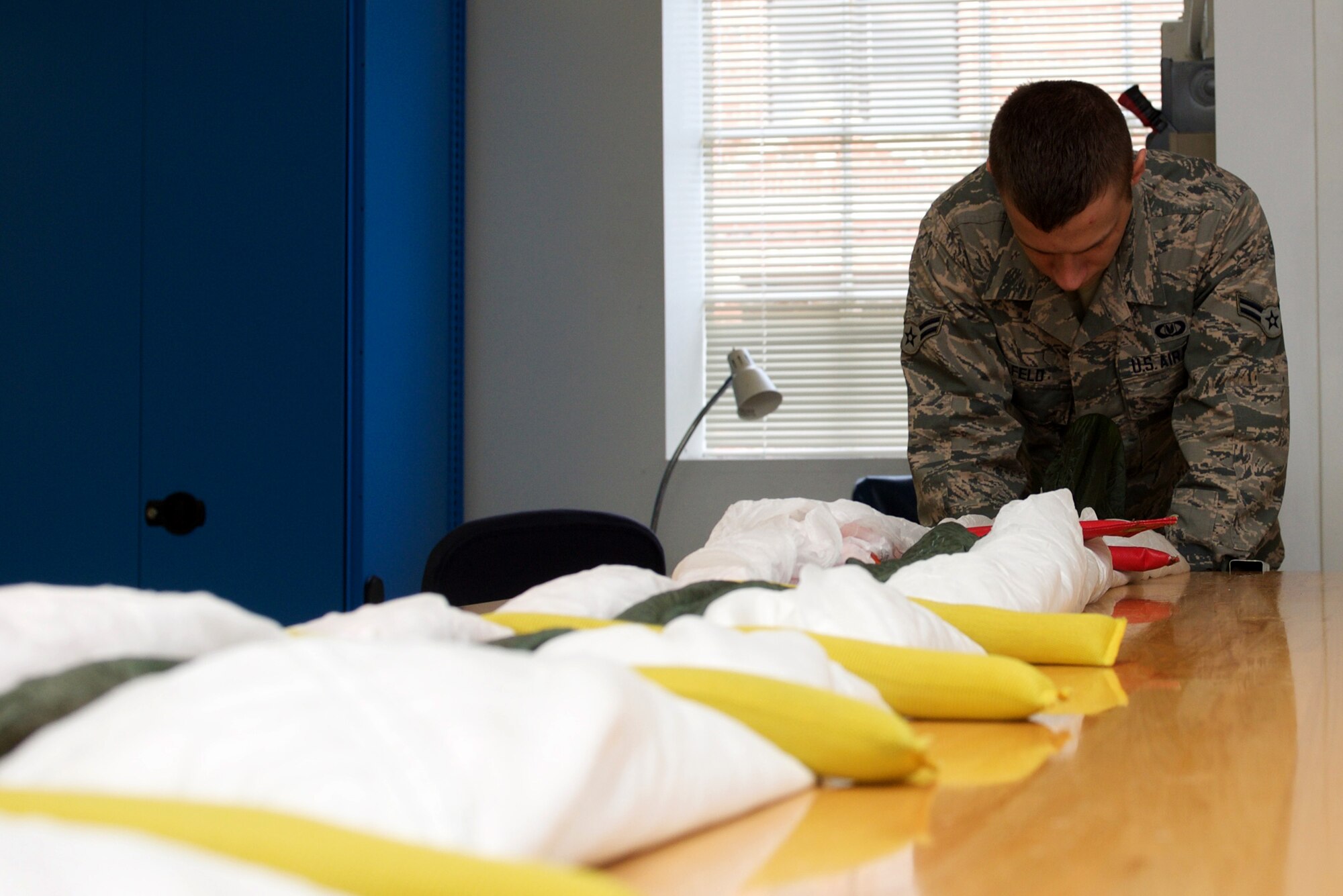 U.S. Air Force Airmen 1st Class Justin Alfeld, 1st Operations Support Squadron aircrew flight equipment technician, packs an Advanced Concept Ejection System II parachute at Langley Air Force Base, Va., Jan. 29, 2016. Parachute technicians must remain with the parachute throughout the entire packing process to ensure no changes are made. (U.S. Air Force photo by Airman 1st Class Derek Seifert)