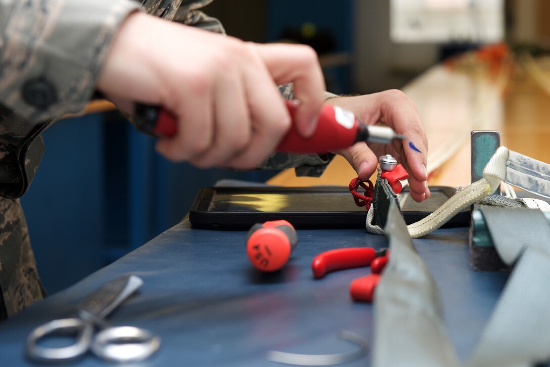 U.S. Air Force Airman 1st Class Justin Alfeld, 1st Operations Support Squadron aircrew flight equipment technician, ties the handles and straps of a parachute into place at Langley Air Force Base, Va., Jan. 29, 2016. Parachute technicians leave a half-inch of slack to help reduce opening force and the pressure put onto a pilot’s body upon ejection. (U.S. Air Force photo by Airman 1st Class Derek Seifert) 